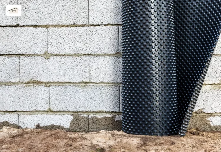 Kurz vor dem Noppenbahn-Verlegen, lehnt die Rolle an einer grauen Mauer.